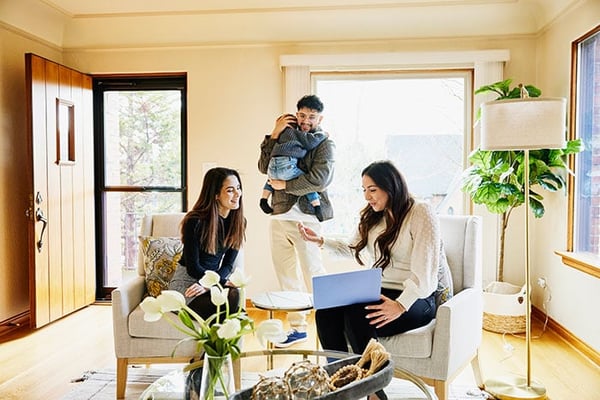 Three adults and child in living room with laptop