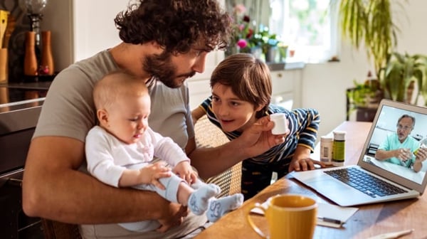 Man at a laptop with children sitting on his lap