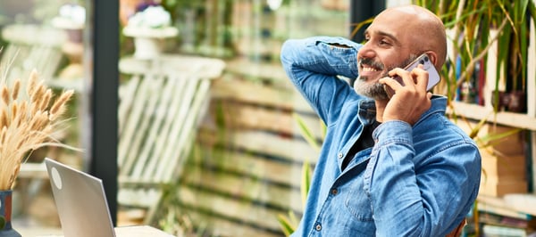 Cheerful businessman talking on mobile phone at home