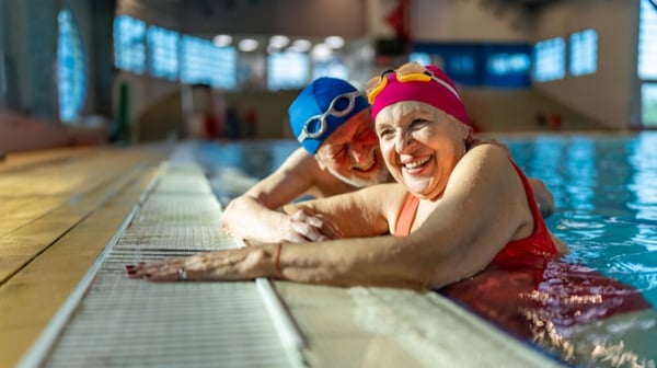 Two senior friends hanging out together in the swimming pool.