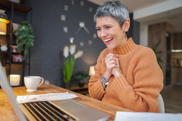 Excited mature woman with short gray hair on her laptop