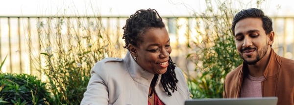 Woman and man looking at laptop whilst outside