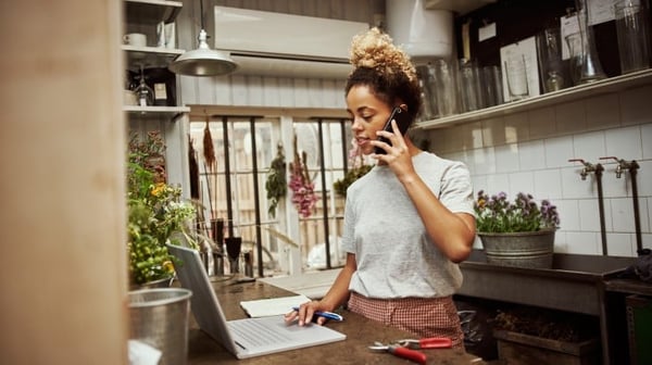 Young woman talking on the phone while using a laptop