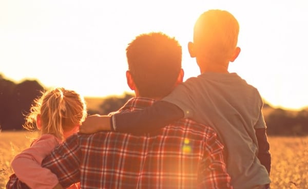 Father with two children looking away in field