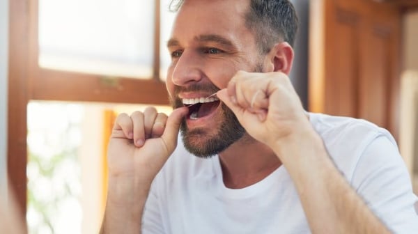 man flossing his teeth