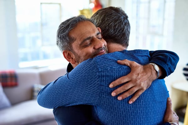 Close up image of 2 men hugging