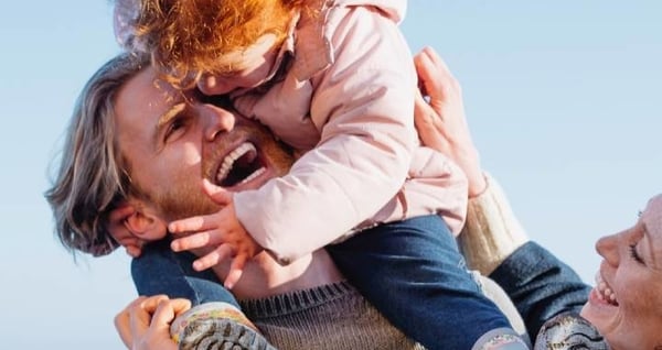 Father and mother holding daughter laughing and smiling