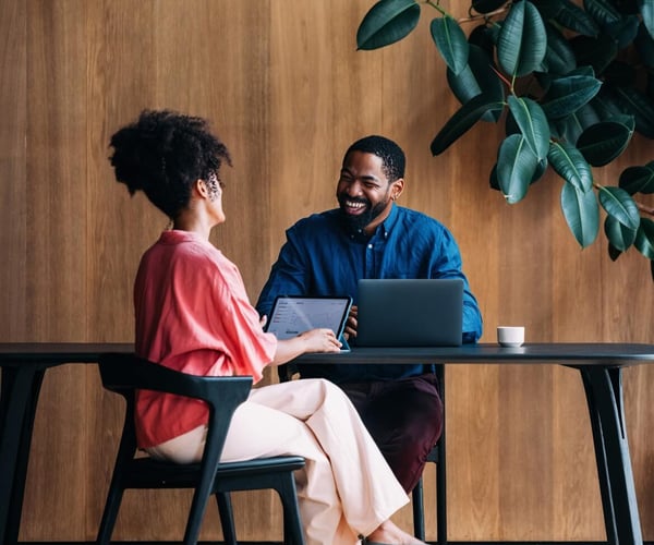A man and a woman laughing while working at a table together