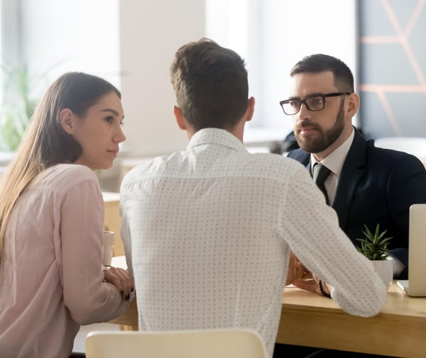 A couple talking to a man over a desk