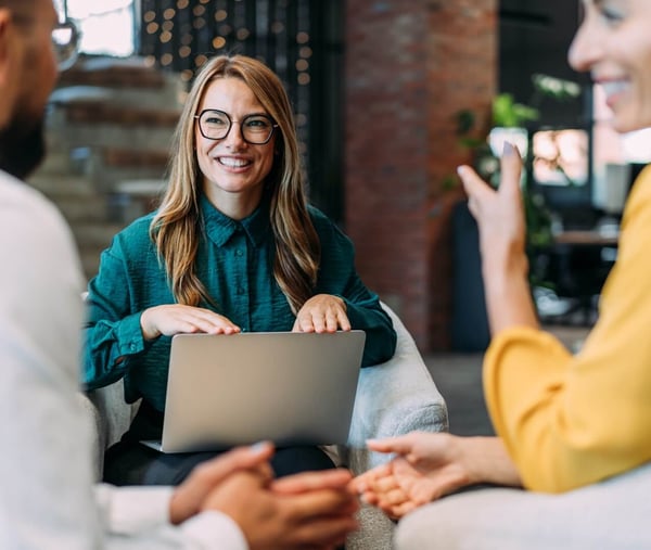 A lady in a teal shirt sat at work, laughing with colleagues