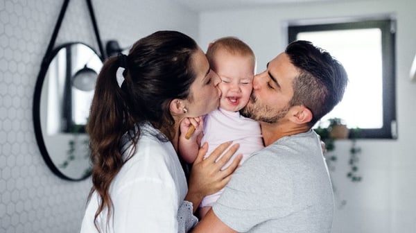 Mum and dad kissing baby in a bathroom