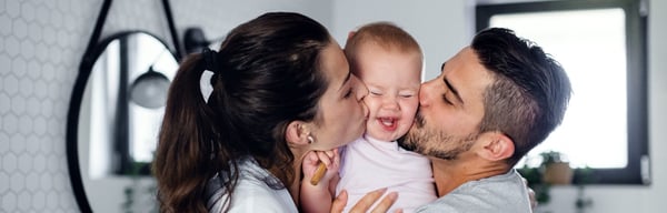 Mum and dad kissing baby in a bathroom