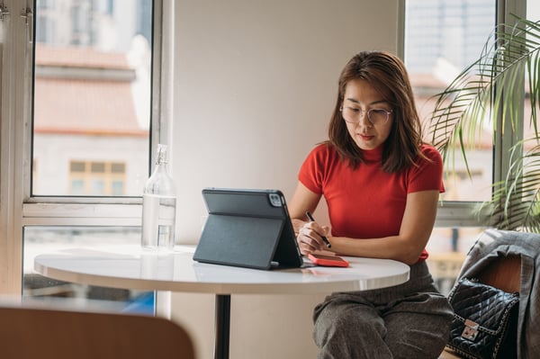 Woman wearing red top in coffee shop looking at ipad