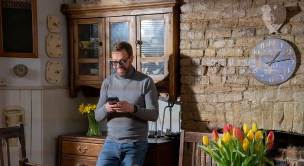 Robert looking at phone and having a cuppa in his kitchen