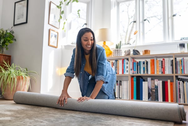 Woman unrolling carpet in her flat