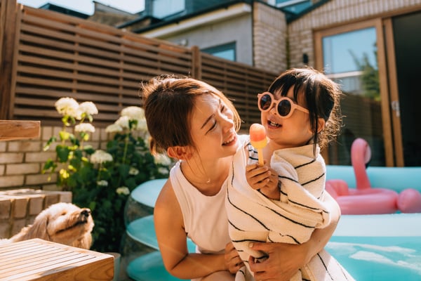 Caring young mother wrapping her toddler daughter in towel after swimming