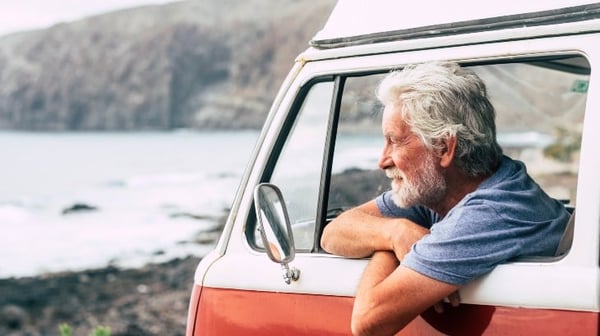 Senior man in vintage camper on holiday