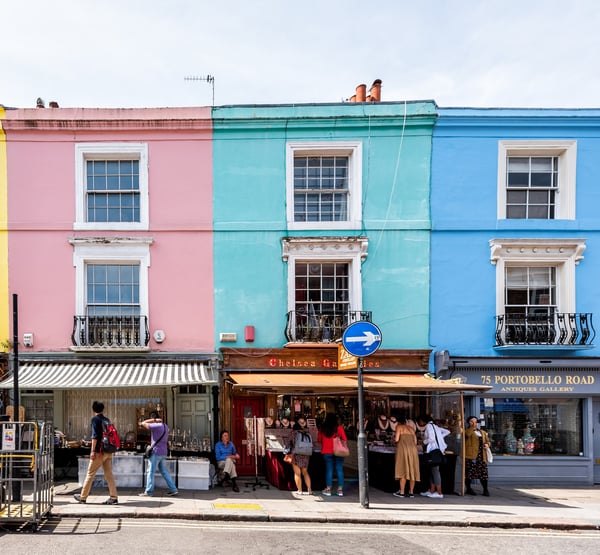 A pink and blue terrace houses, with shops at the bottom at Portobello Road market