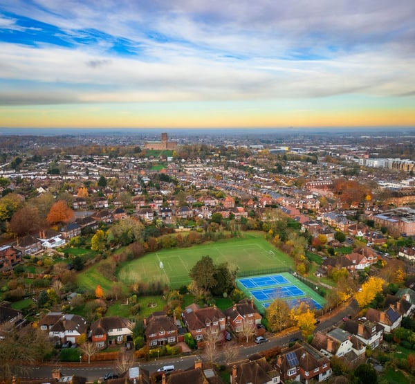 A birds eye view of a town, with a football pitch and tennis courts in view