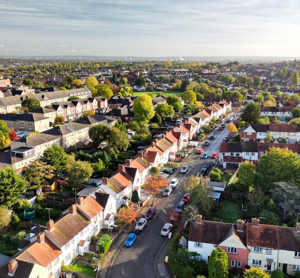 A birds eye view of a town, focusing on a street with terraced houses and parked cars