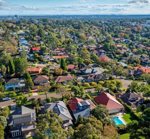 A birds eye view of detached houses with trees and swimming pools