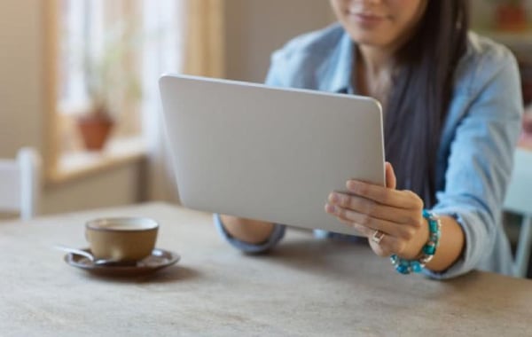 Woman at kitchen table with computer tablet
