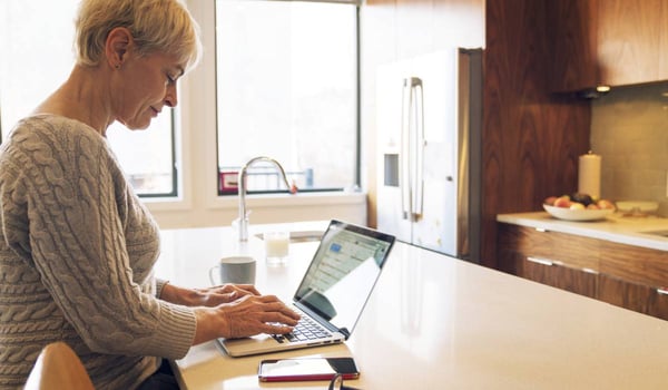 Woman using laptop on kitchen table