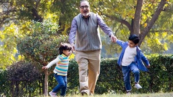 Grandfather holding hands with grandchildren in the park