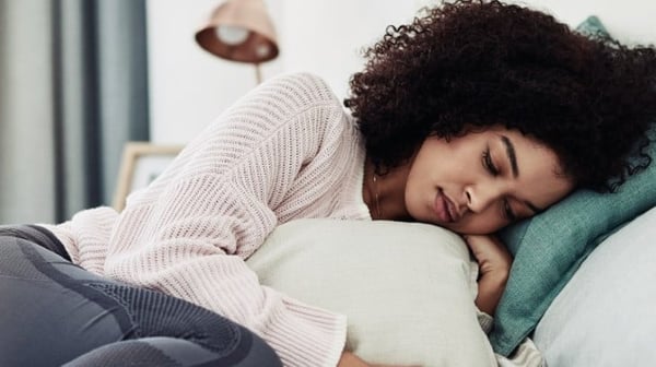 Woman lying on bed holding a cushion