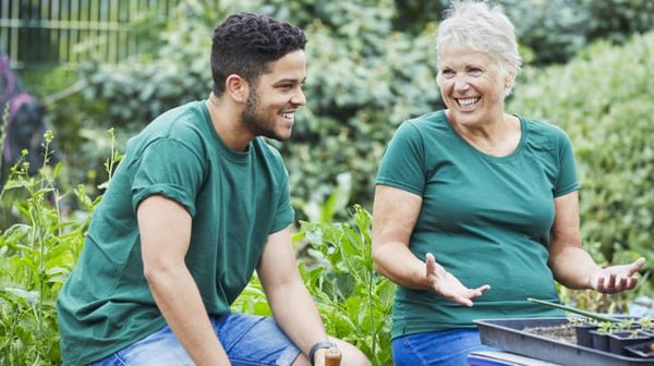 Young man and older woman taking a break from gardening.