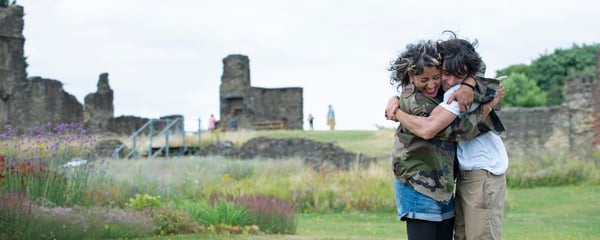 A woman and a boy hugging in a field