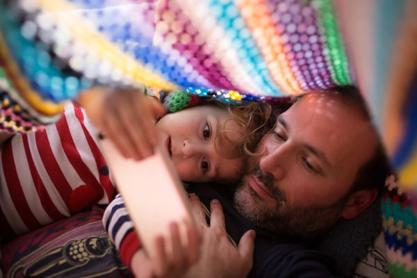 Close up of a father and his child reading under a blanket