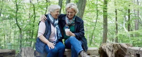 Two women laughing sat in the woods