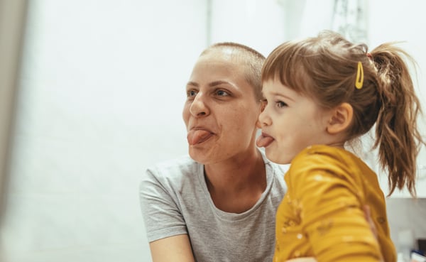 Woman with cancer having fun with young daughter