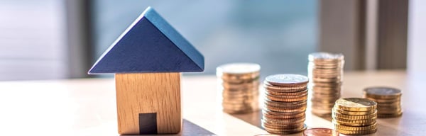 Stacks of coins next to toy wooden house