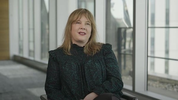 Woman sitting down with office windows behind