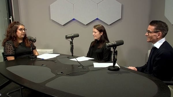 People sat around a table in a recording studio