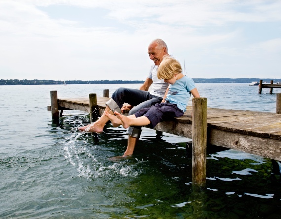 Boy splashing with grandfather at lake