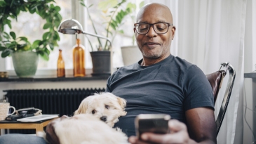 Retired senior male with dog in room at home