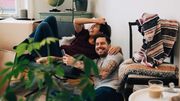 A couple laughing at home surrounded by boxes after just moving in