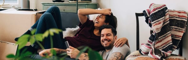A couple laughing at home surrounded by boxes after just moving in
