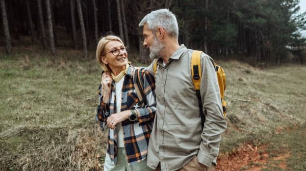 Mature hiking couple walking together across open field