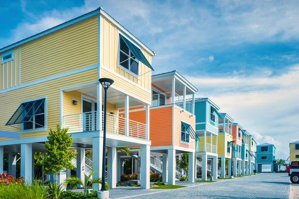 A series of colourful, raised holiday homes with balconies by the water