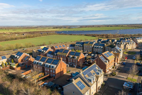 A birds eye view of new build houses int he countryside, with solar panels on the roofs