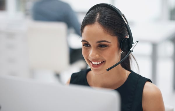 A young lady working at a computer with a headset on
