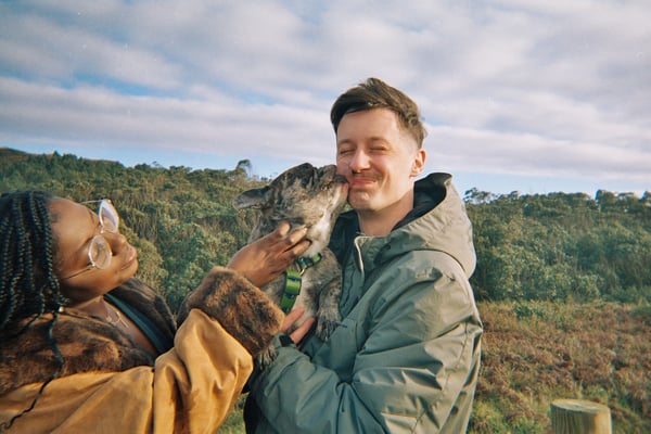 Couple laughing as a dog licks the owners face