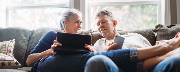 Mature couple relaxing with tablet and smartphone