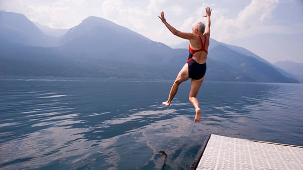 Retired woman jumping into the lake