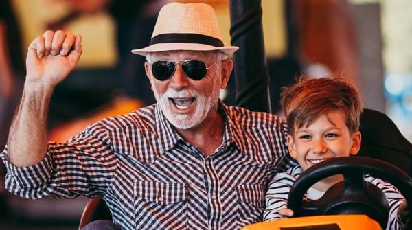 Image of grandfather and grandson having fun on ride at the fairground