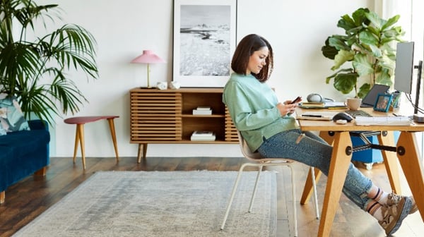 Image of a young woman sat at desk looking at mobile phone
